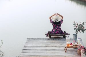 The girl wearing a red floral dress sitting on the waterfront wi